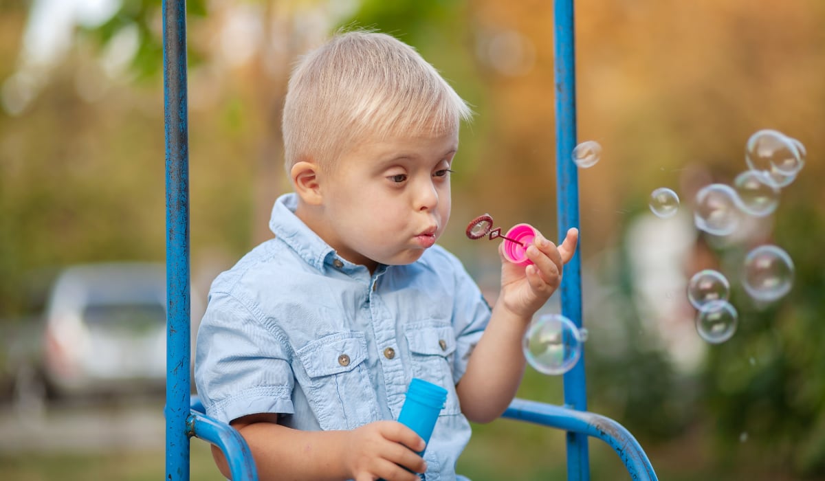 A young boy with Downs syndrome playing on a swing
